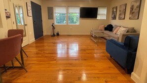 A spacious living room with hardwood flooring, a sofa, a coffee table, and a TV mounted on the wall. - Chic 5-bedroom/ 2 B apartment in Washington with AC, WiFi (Washington)