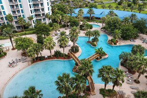 A resort with multiple swimming pools surrounded by palm trees and lounge areas. - 🌴Lagoon Pool View~ Palms 2715 ~ Nearby Beach☀️ (Destin)