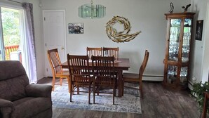 Ein Essbereich mit Holztisch und Stühlen, einer Kristallleuchtre und einem dekorativen Kranz an der Wand.