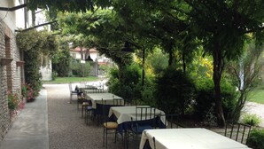 An outdoor seating area with tables and chairs, surrounded by greenery and a gravel path. - La Vie en Rose Resort (San Vito al Tagliamento)