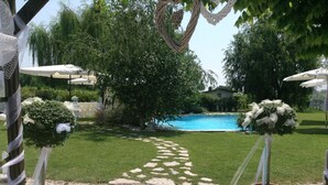 A backyard with a swimming pool, a stone pathway, and potted plants. - La Vie en Rose Resort (San Vito al Tagliamento)