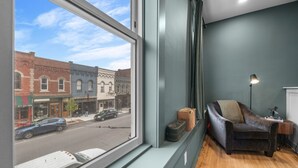 A room with a large window, a leather sofa, a lamp, and a suitcase. - Modern Studio - Main St Penn Yan (Penn Yan)