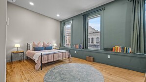 A bedroom with a bed, bedside tables, a round rug, a window with curtains, and a bookshelf. - Modern Studio - Main St Penn Yan (Penn Yan)