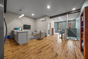 A spacious living area with a kitchen, a sofa, and a dining table. - Modern Studio - Main St Penn Yan (Penn Yan)