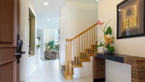 A hallway with a wooden staircase, a reception desk, and a framed picture on the wall. - Includes Beach Gear!  2404 Waikoloa Colony Villas (Waikoloa Beach Resort)