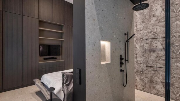 Une salle de bain moderne dotée d’une douche, d’un téléviseur intégré et d’un design minimaliste.