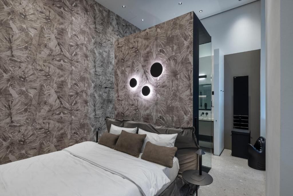 Ein modernes Schlafzimmer mit einem großen Bett, einem Nachttisch und einer Wand mit runden Leuchten.