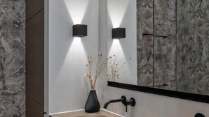 Une salle de bain moderne avec un pare-baignoire en marbre, un grand miroir et deux lavabos.
