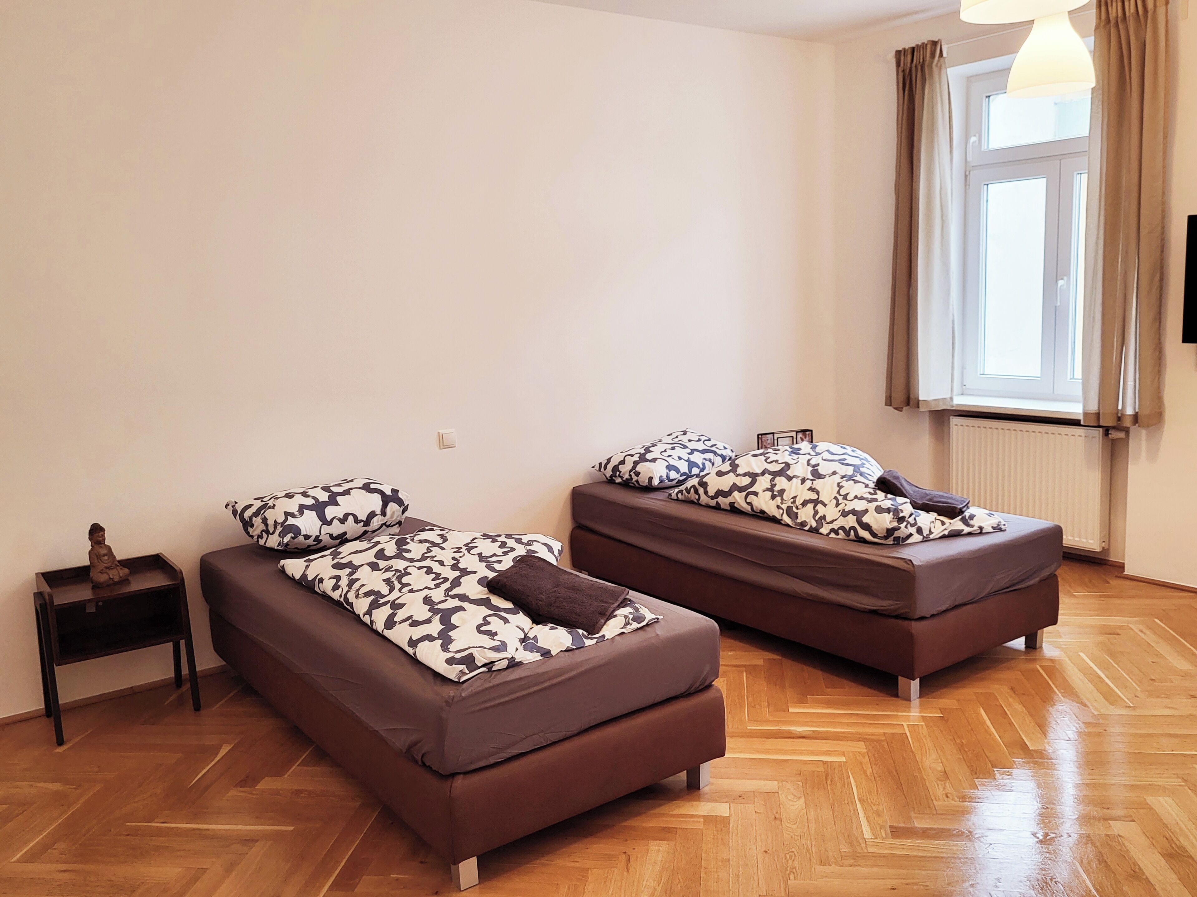 Een kamer met twee eenpersoonsbedden, een tafeltje en een beeld.