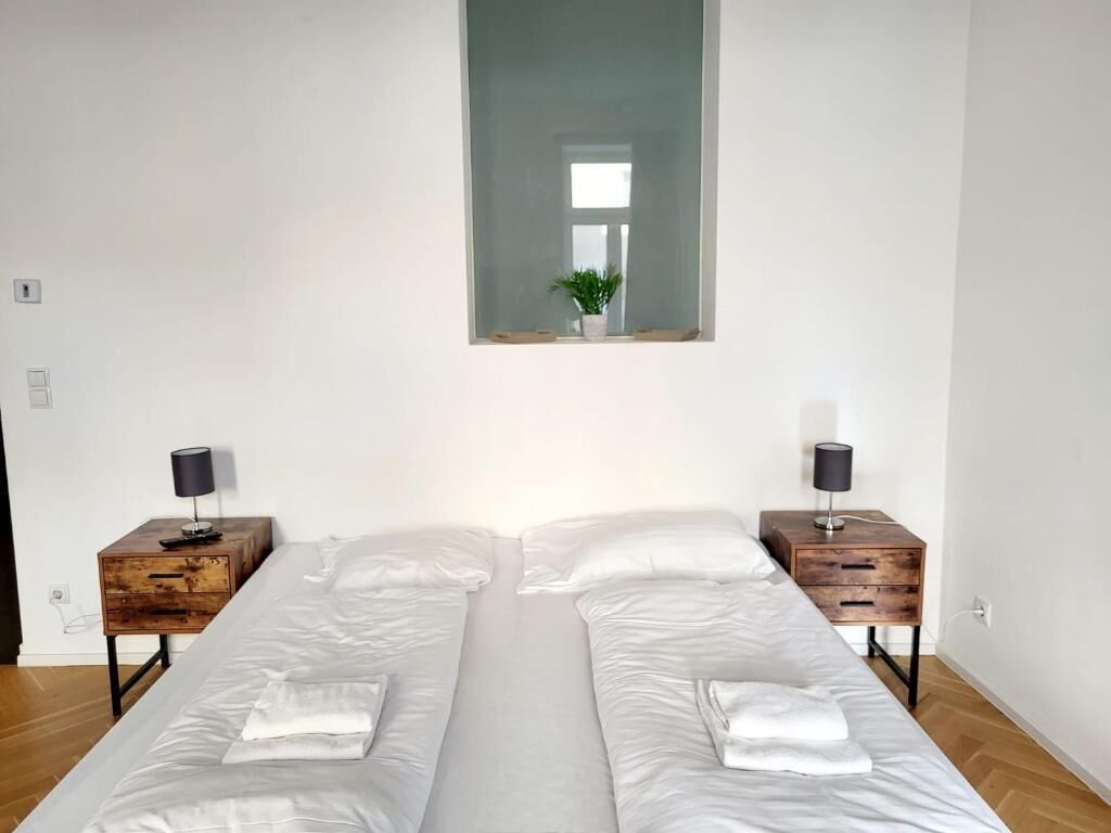 Un dormitorio con dos camas, un espejo sobre ellas y una ventana.
