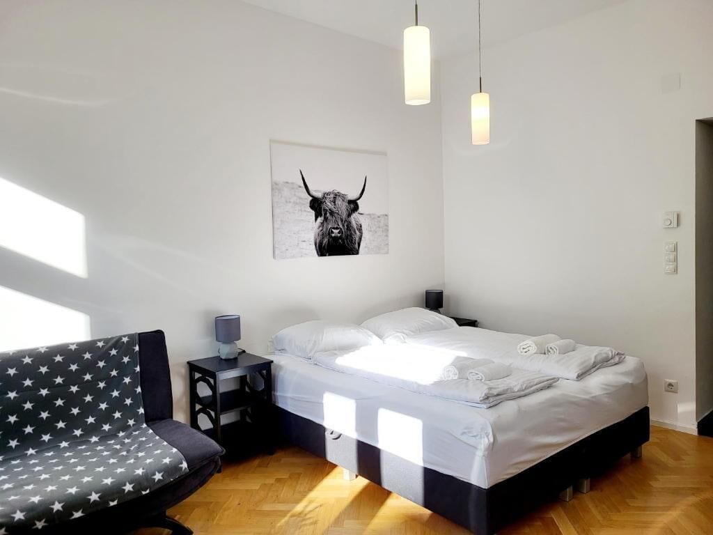 A modern bedroom with a bed, bedside table, lamp, and a star-patterned sofa.
