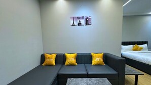 A modern hotel room with a sectional sofa, a small table, and a bed. - Lime Tree Hotel Sector 51 Gurgaon (Gurugram)