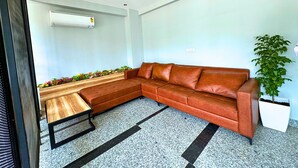 A modern office space with a leather sofa, a wooden table, and a potted plant. - Lime Tree Hotel Sector 51 Gurgaon (Gurugram)