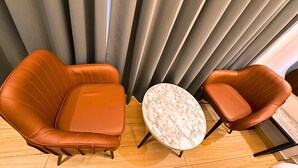 A room with two brown leather armchairs and a marble round table. - Lime Tree Hotel Sector 51 Gurgaon (Gurugram)