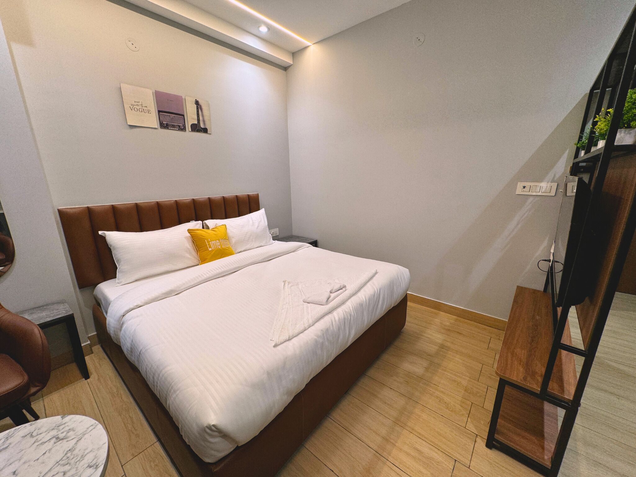 Une chambre à coucher bien rangée, avec un grand lit, une petite table de chevet, une chaise et un meuble pour la télévision.