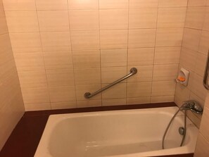 Un baño con bañera, barras de apoyo y cabezal de ducha.