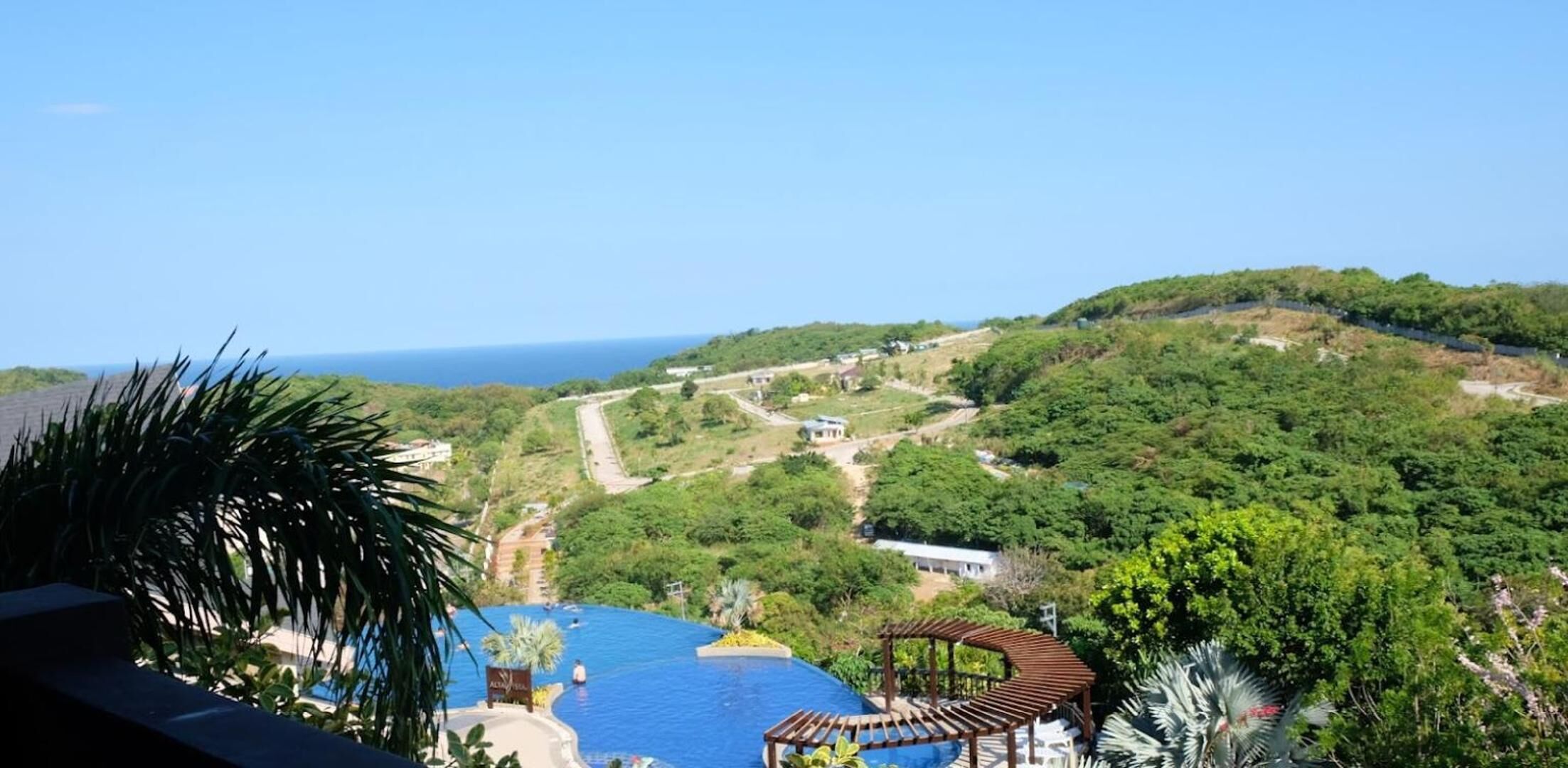 Un resort con piscina, un pabellón y vistas al océano y las colinas.