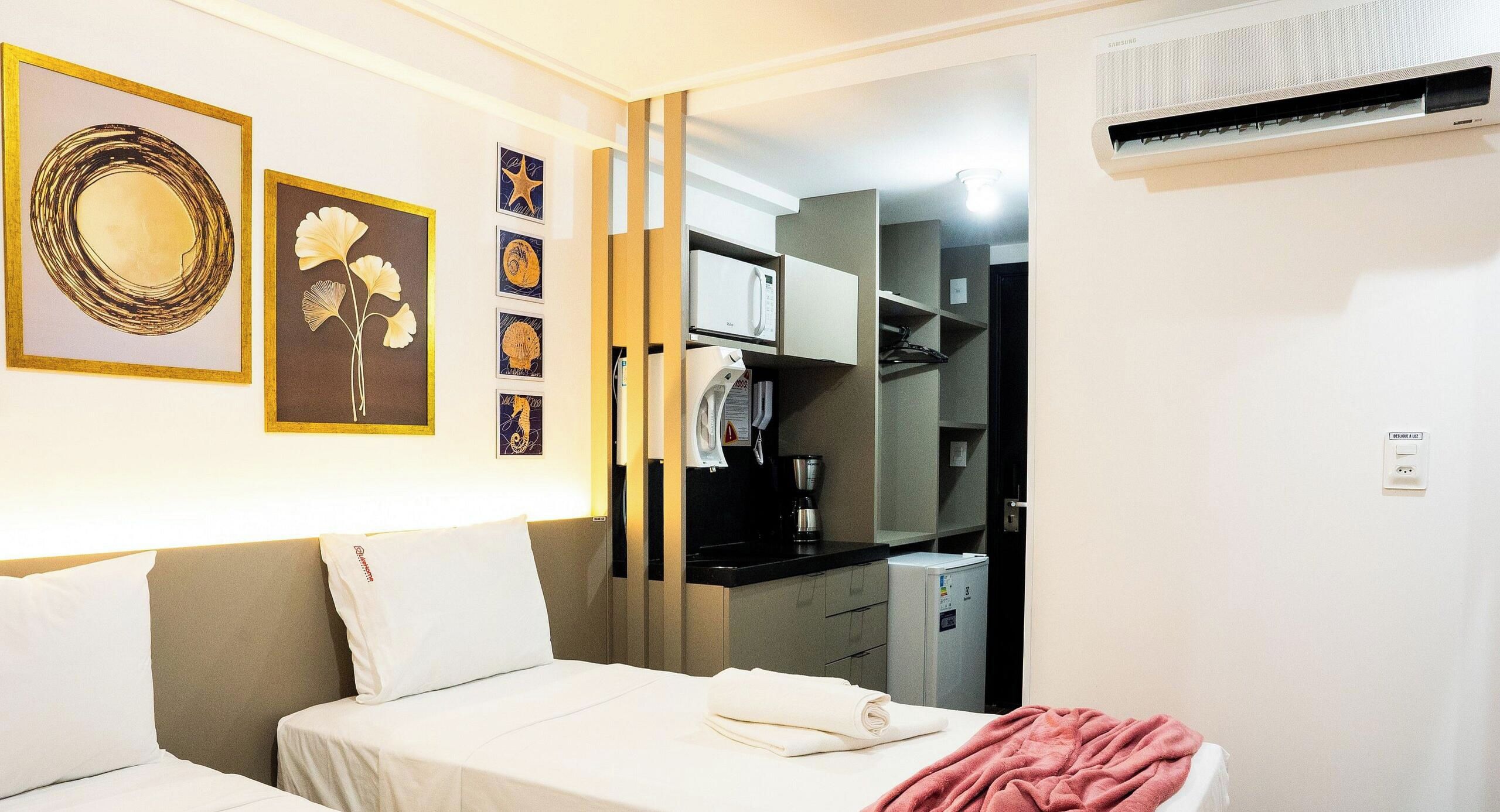 Een hotelkamer met een bed, een bureau, een magnetron en een kitchenette.