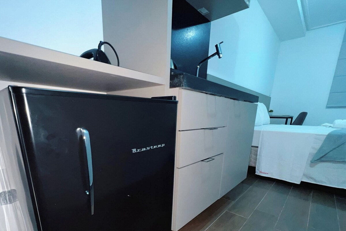 A compact kitchen with a black refrigerator, white cabinets, and a small countertop.