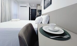 A hotel room with a bed, a bedside table with a cup and saucer, and a pillow. - Move Tambaú (João Pessoa)
