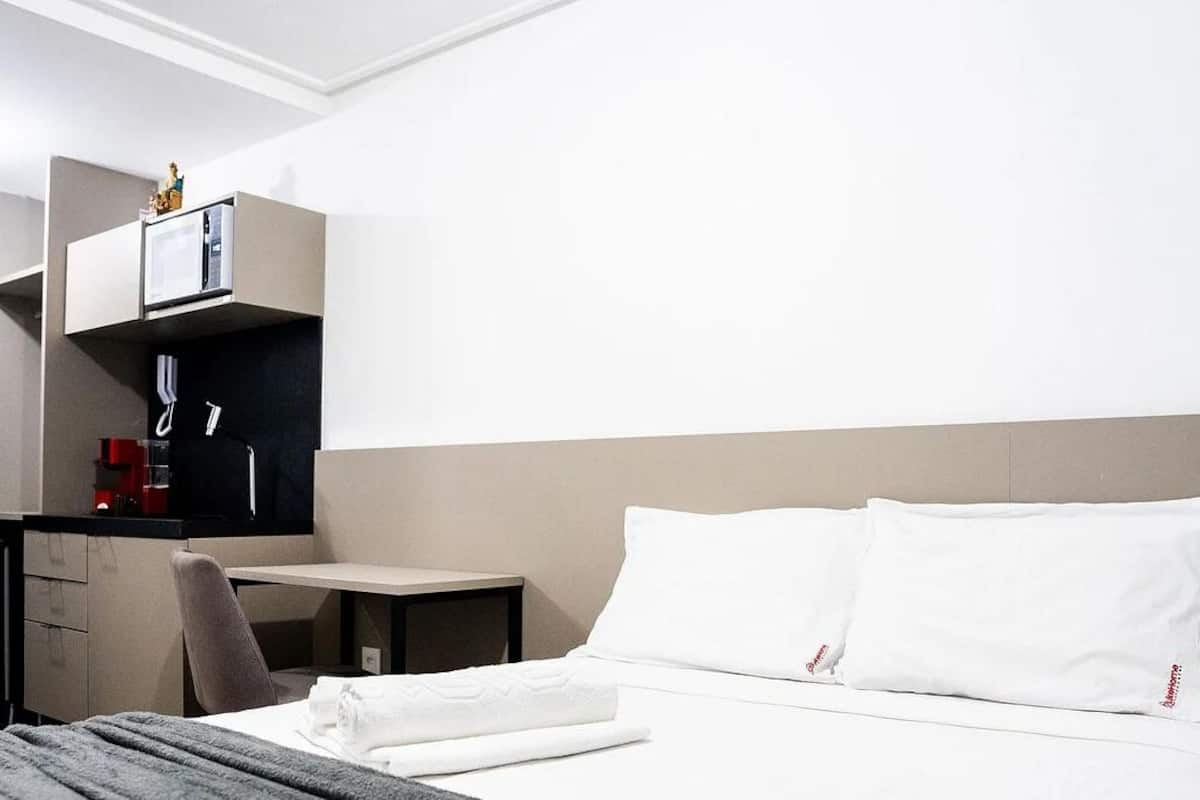 Ein Hotelzimmer mit Bett, Schreibtisch, Stuhl, kleinem Tisch und einer Minibar.