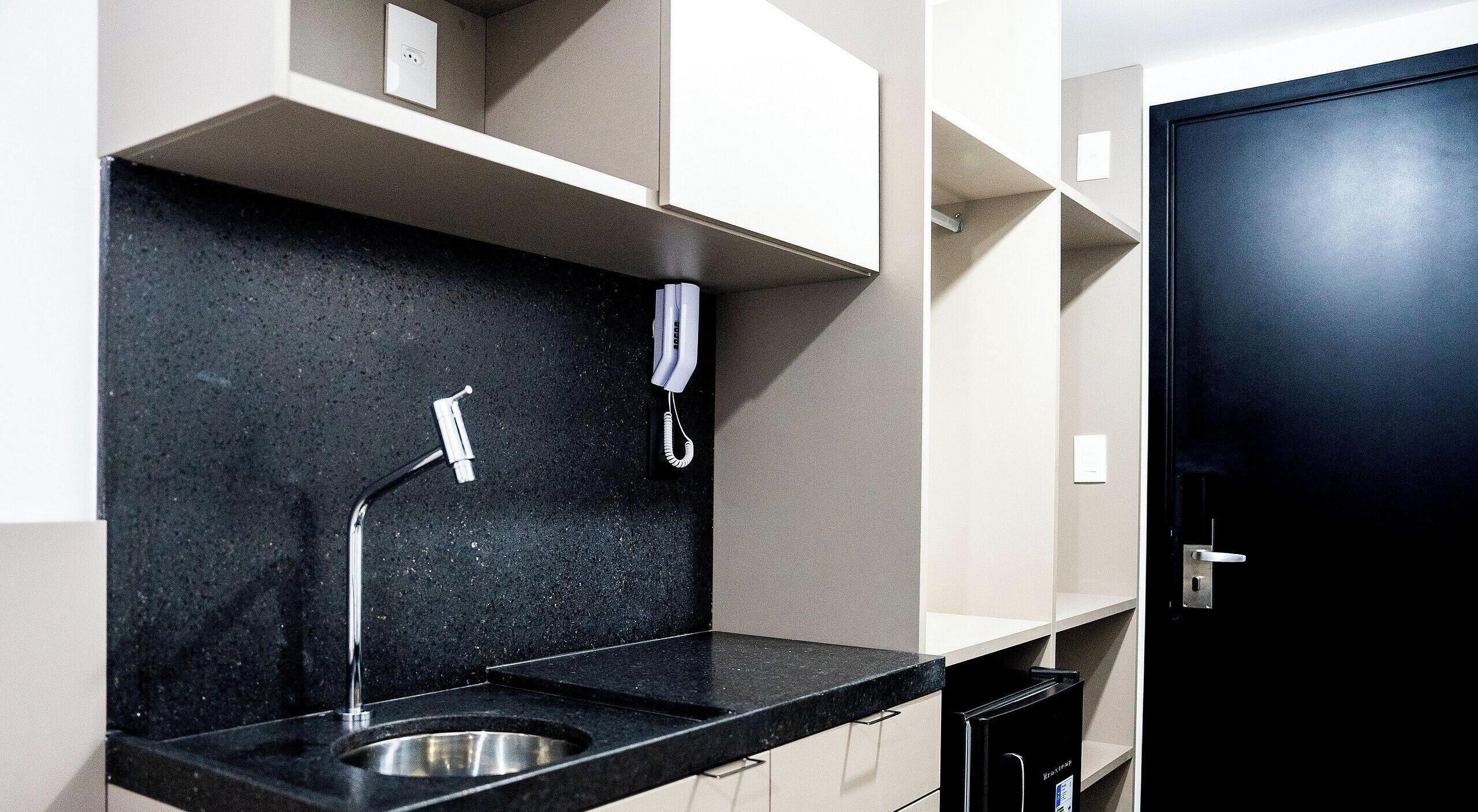 A modern kitchen with a black countertop, stainless steel sink, and a black cabinet.