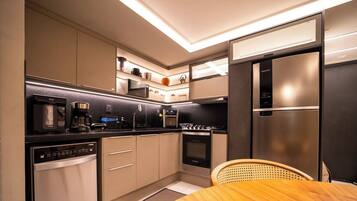 A modern kitchen with a dishwasher, coffee maker, microwave, oven, and a stainless steel refrigerator.