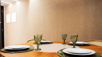 A dining table set for four with four wine glasses and plates, in a room with a textured wall and a door visible to the left.