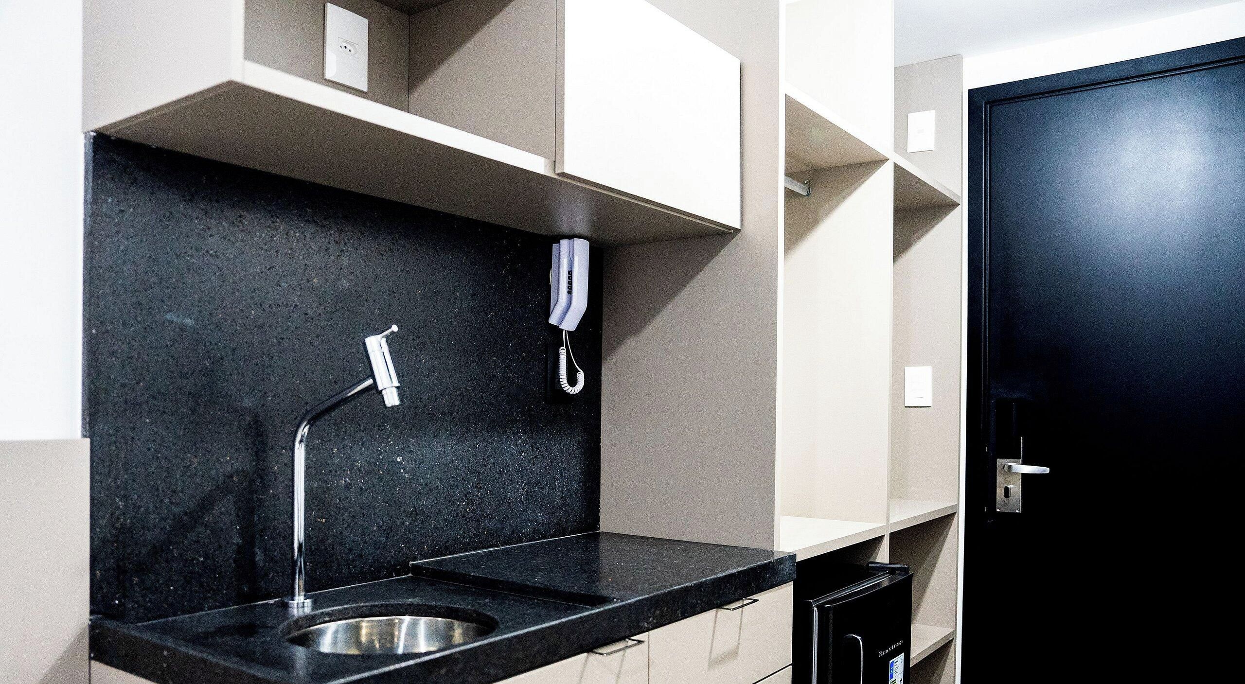 A modern kitchen with a black countertop, stainless steel sink, and a black cabinet.