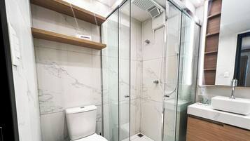 Une salle de bain moderne dotée d’une douche à parois de verre, de toilettes et d’un meuble-lavabo avec un miroir.