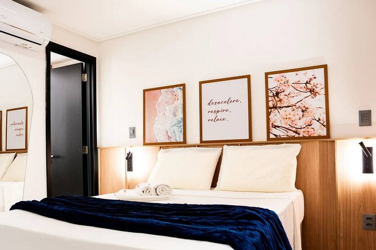 Ein Hotelzimmer mit Bett, Nachttisch, Spiegel und Wandbildern.