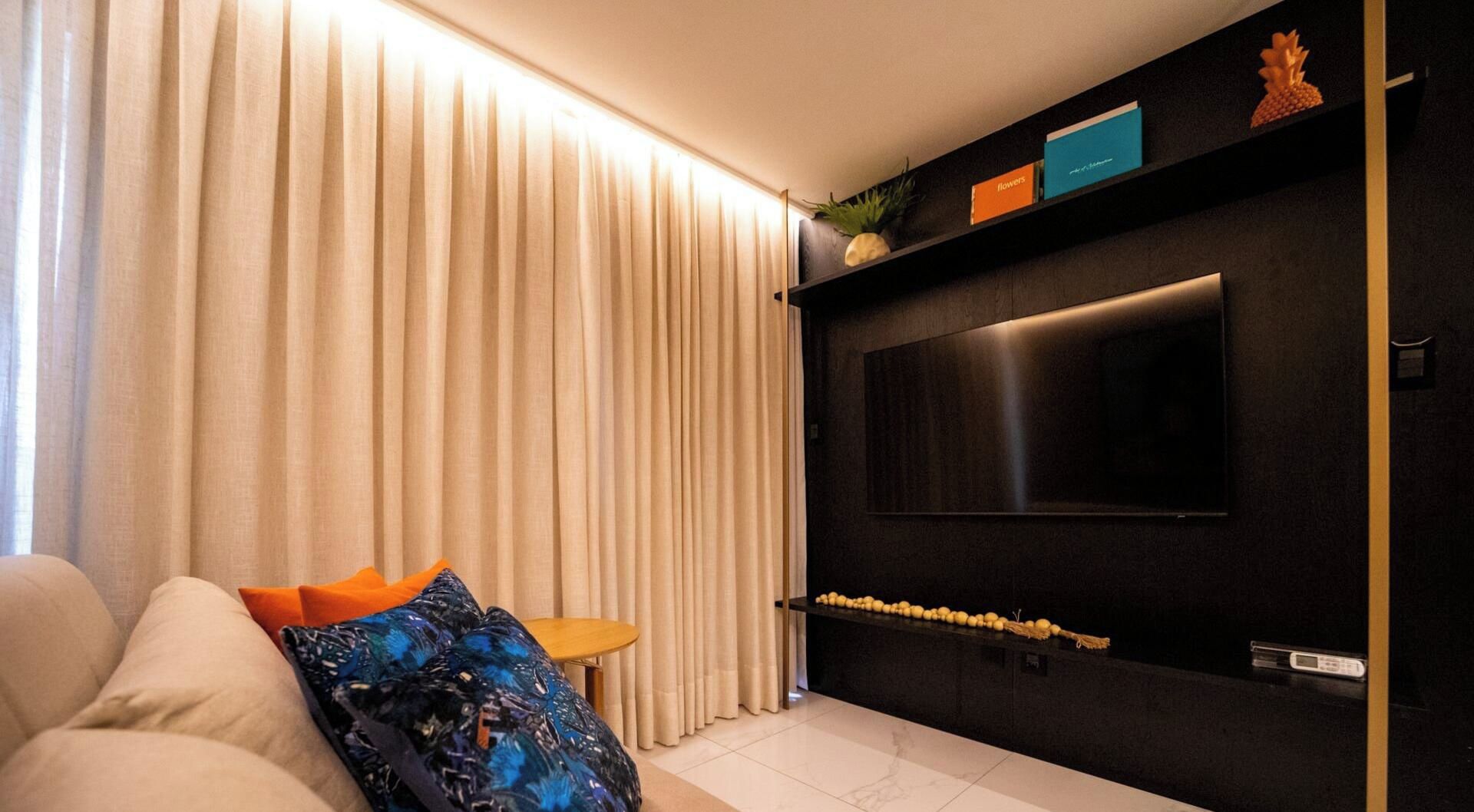 A modern living room with a sofa, a coffee table, and a TV mounted on a dark wall.
