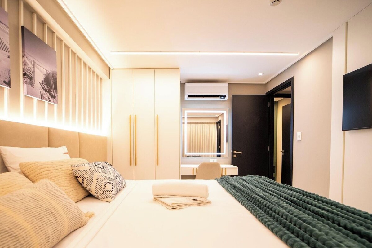 Una habitación de hotel moderna con cama, mesitas de noche, escritorio y televisor de pantalla plana.