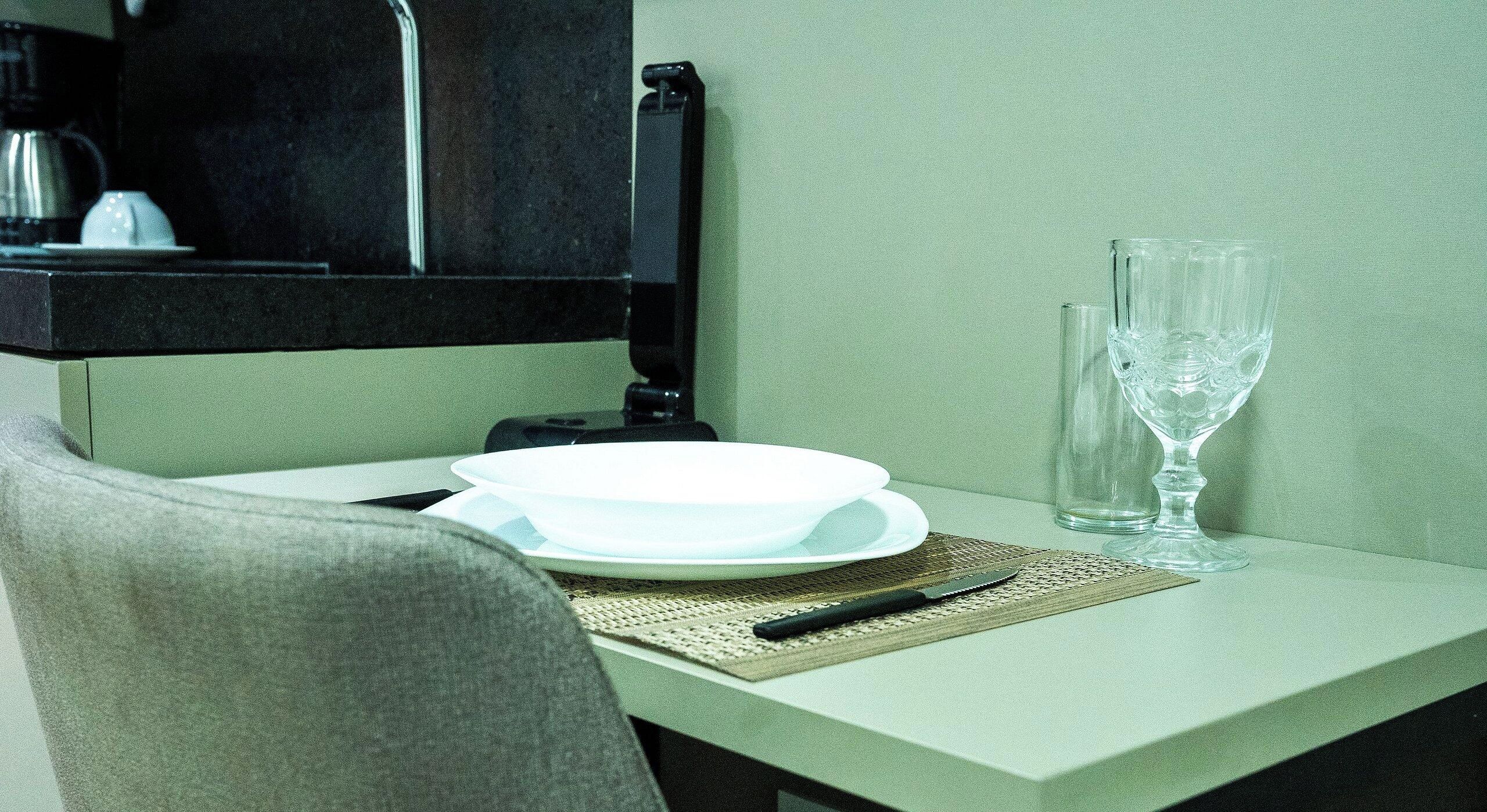 A table with a plate, a knife, a glass, and a bottle.