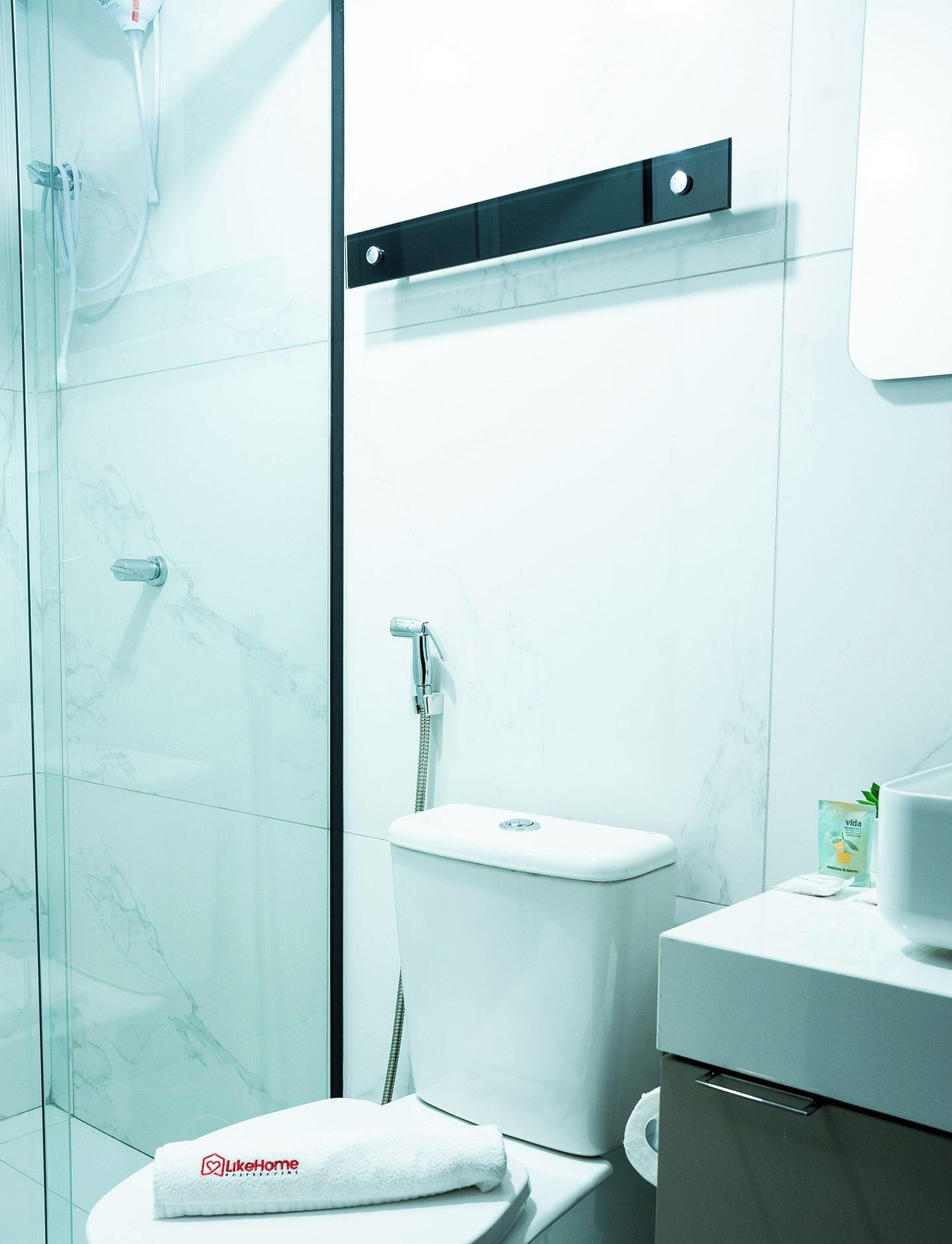 Un baño moderno con cabina de ducha de vidrio, inodoro y lavabo con espejo.