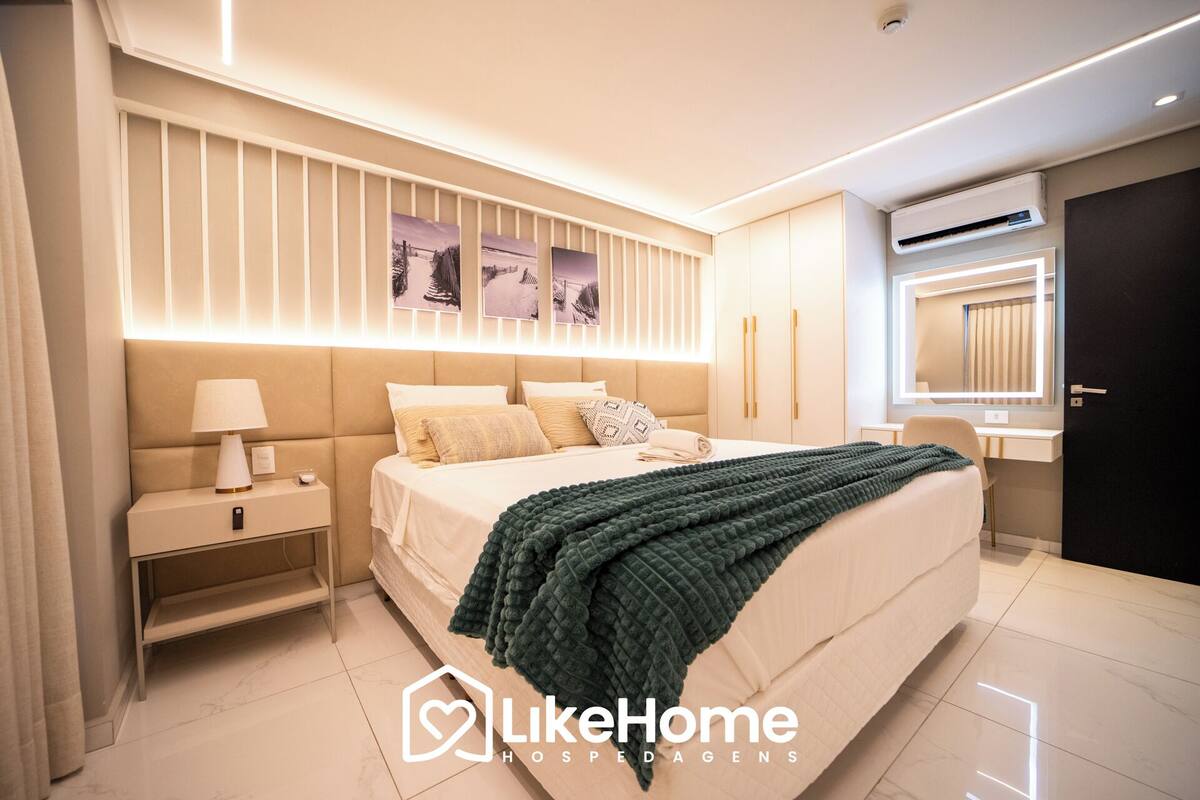 Ein modernes Schlafzimmer mit einem großen Bett, Nachttischen, einem Schminktisch mit Spiegel und Wandbildern.