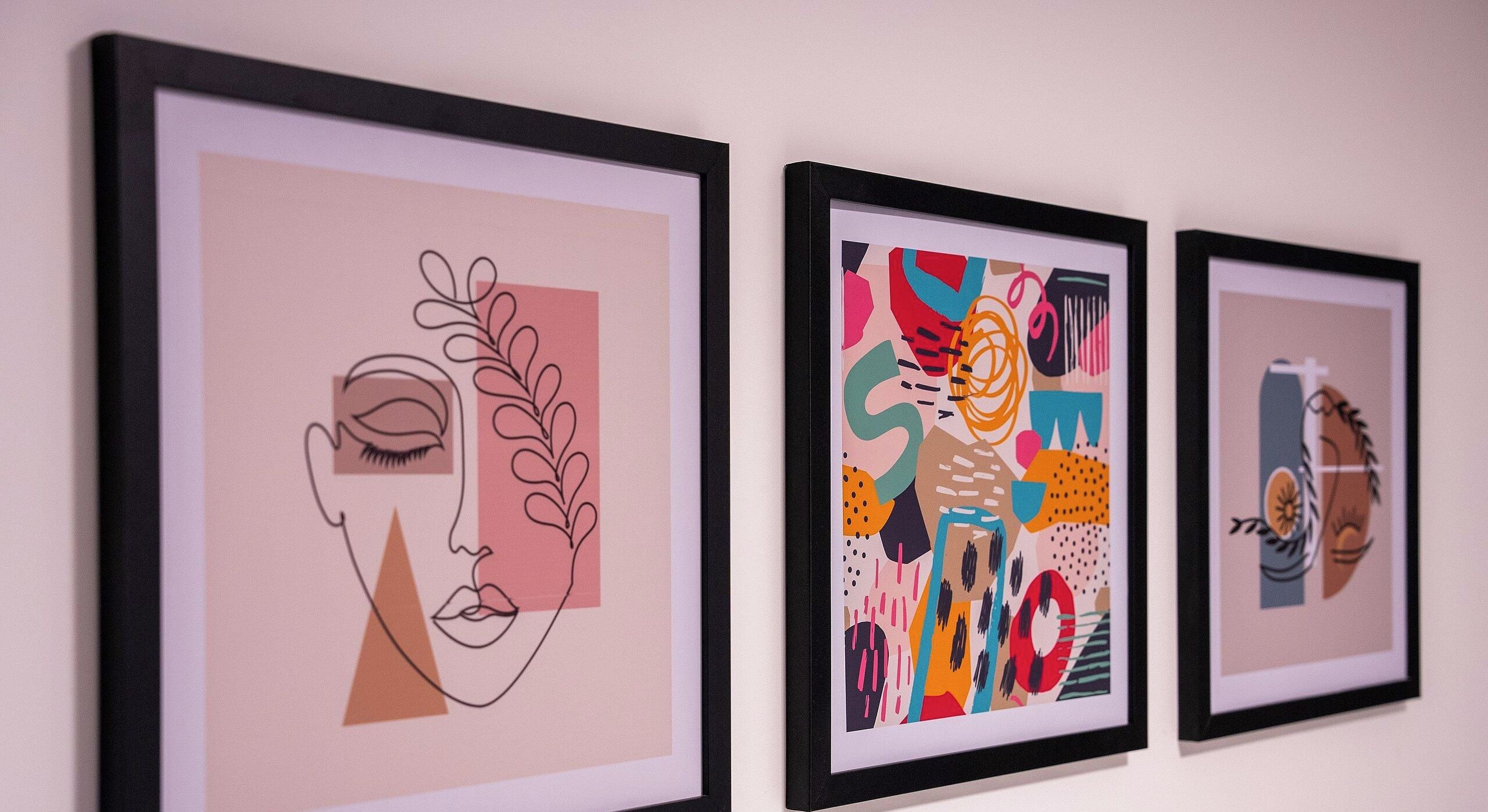 Três obras de arte emolduradas numa parede.