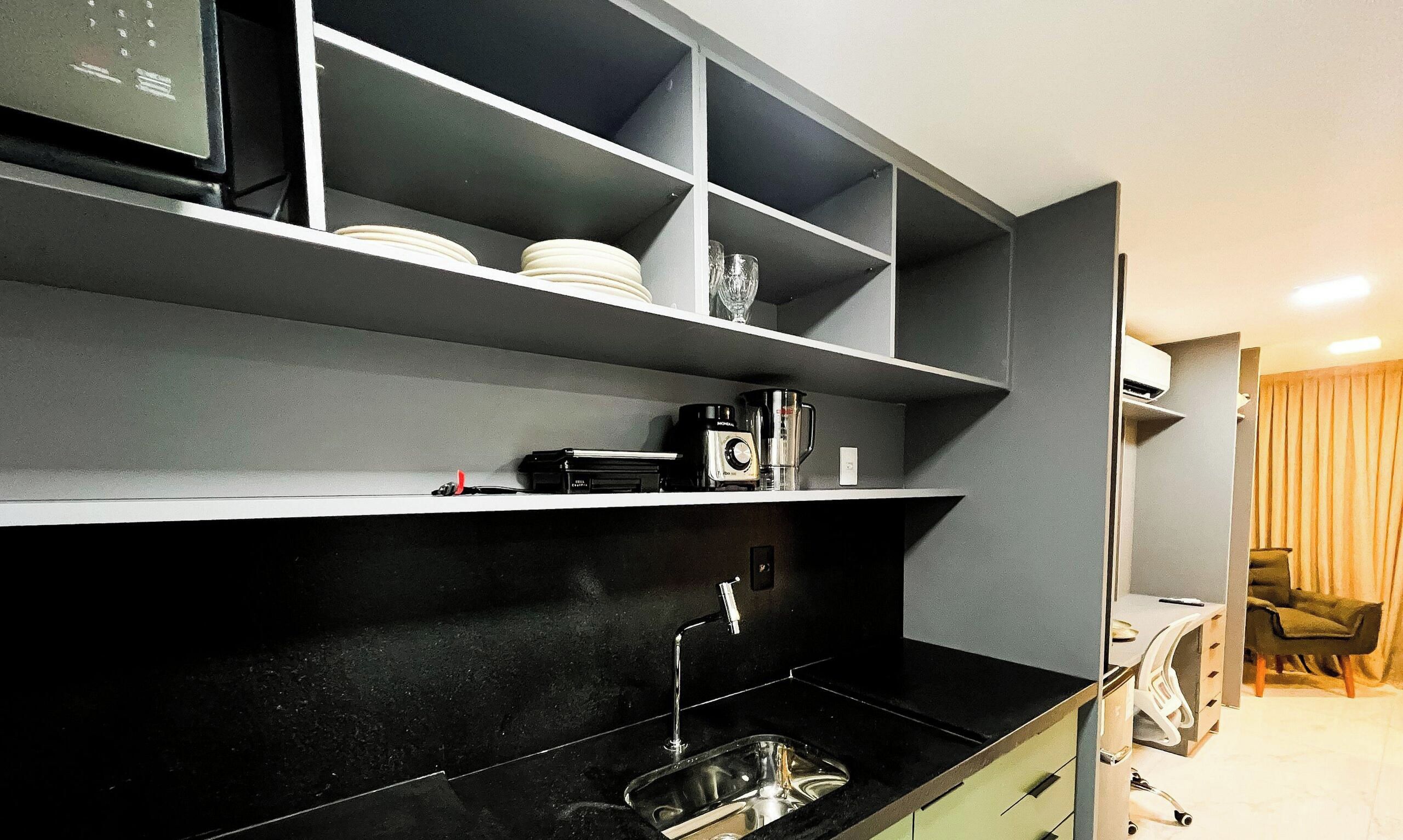 A modern kitchen with black countertops, a stainless steel sink, and built-in shelves.