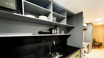 A modern kitchen with black countertops, a stainless steel sink, and built-in shelves.