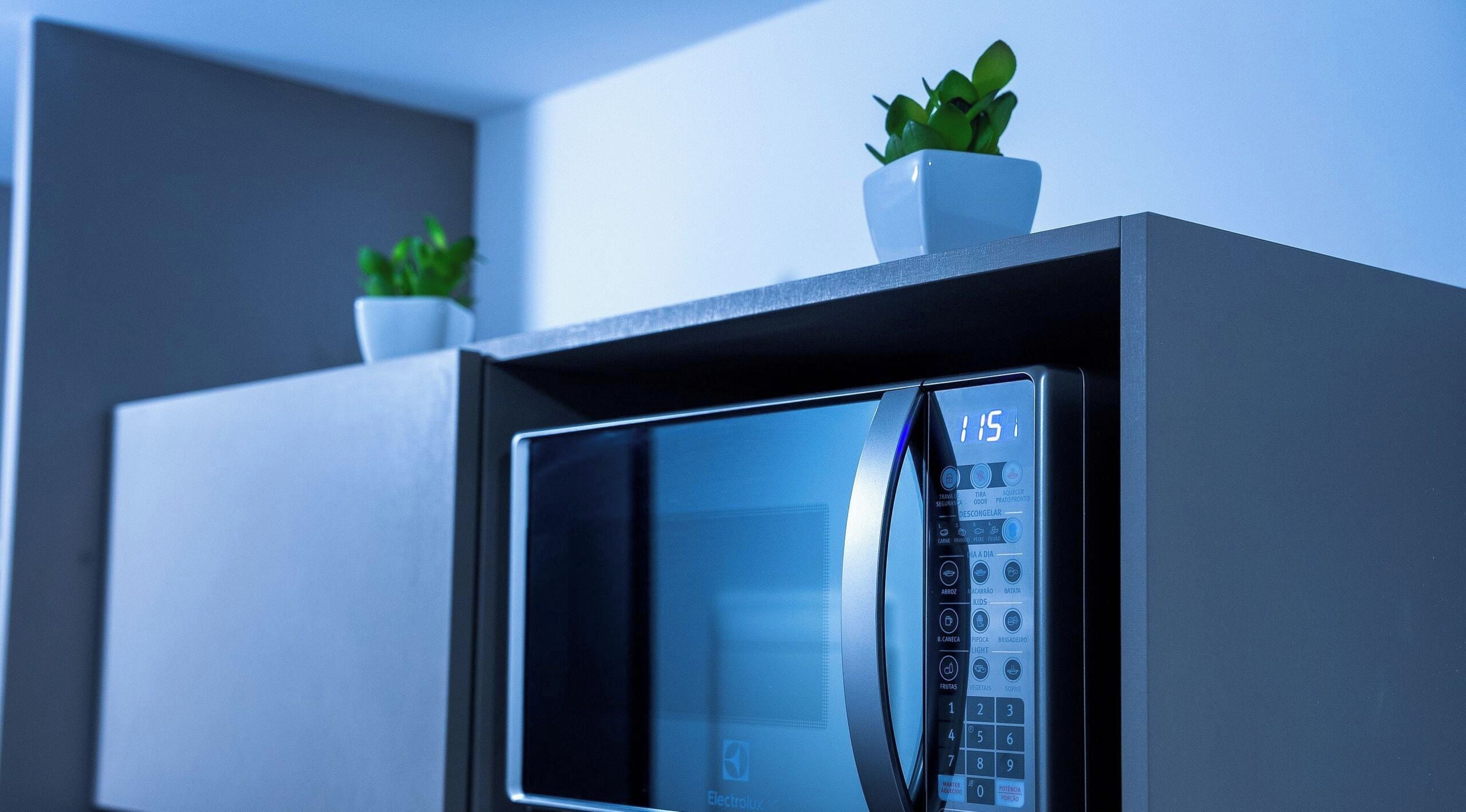 A modern microwave with a digital display and control panel, placed on a kitchen counter.