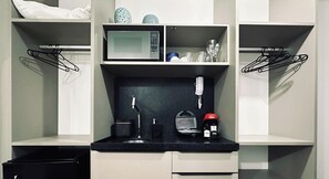 A compact kitchenette with a microwave, coffee maker, and tea kettle. - Move Tambaú (João Pessoa)