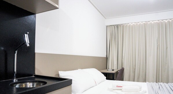 A hotel room with a bed, a desk, a chair, a sink, and a window with curtains. - Move Tambaú (João Pessoa)