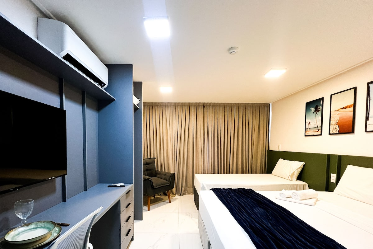 A hotel room with a bed, a desk, a chair, and a TV.