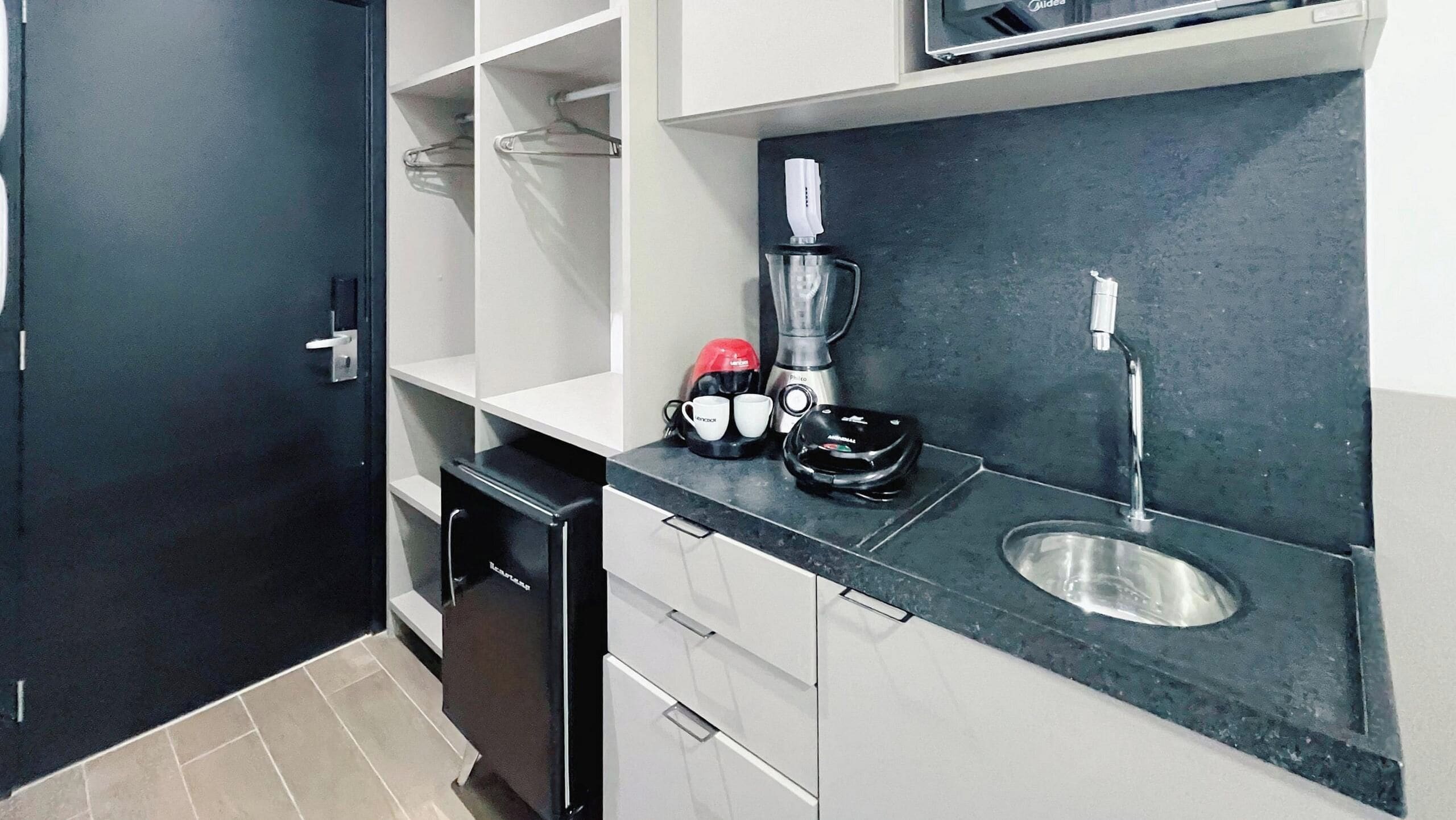 A compact kitchen with a black dishwasher, a sink, and a coffee maker.