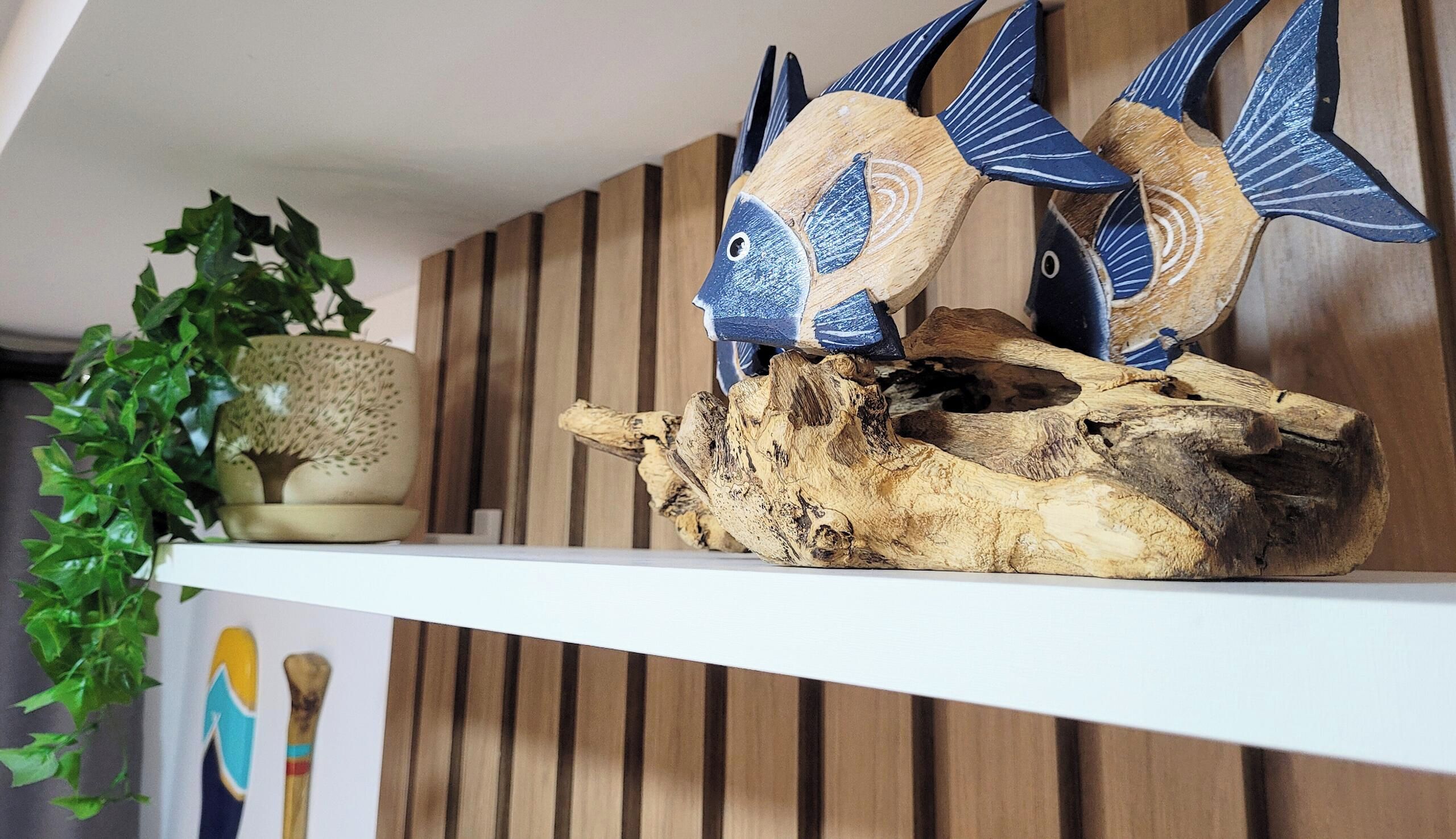 A shelf with decorative fish figures and a plant.