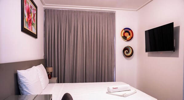 A hotel room with a bed, a TV, a painting, and a curtain. - Move Tambaú (João Pessoa)