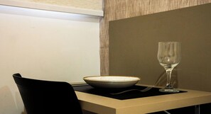 A table with a bowl and a wine glass, a fork, and a black chair. - Move Tambaú (João Pessoa)