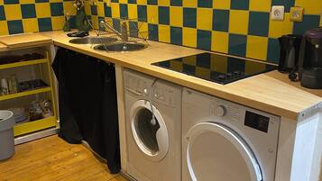 Une cuisine compacte équipée d’un lave-linge, d’une machine à café et d’un évier.