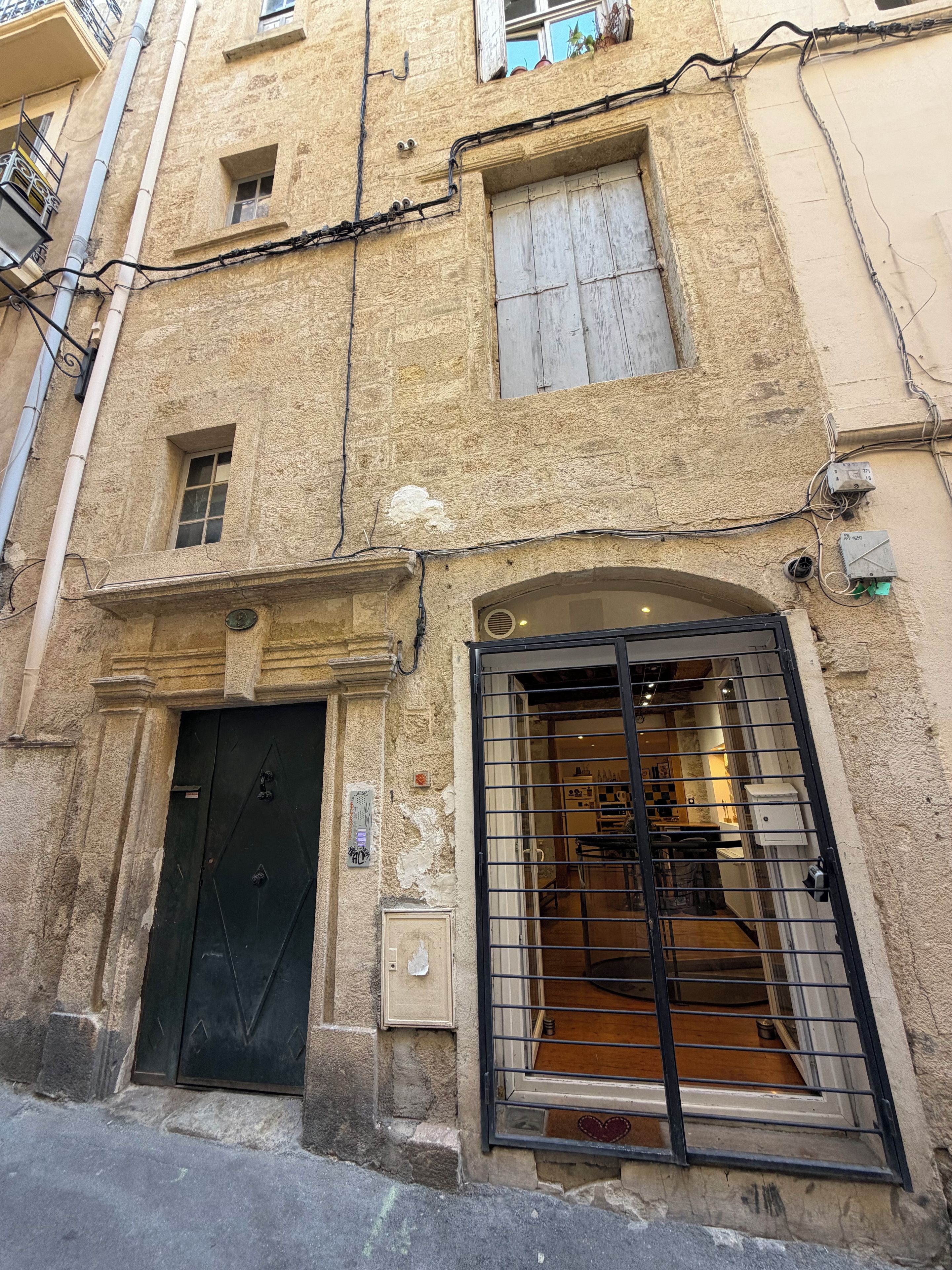 Un bâtiment doté d’un portail en métal noir, d’une petite fenêtre et d’une porte.