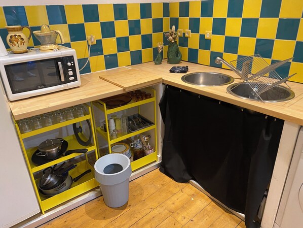 A compact kitchen with a microwave, sink, and various utensils.